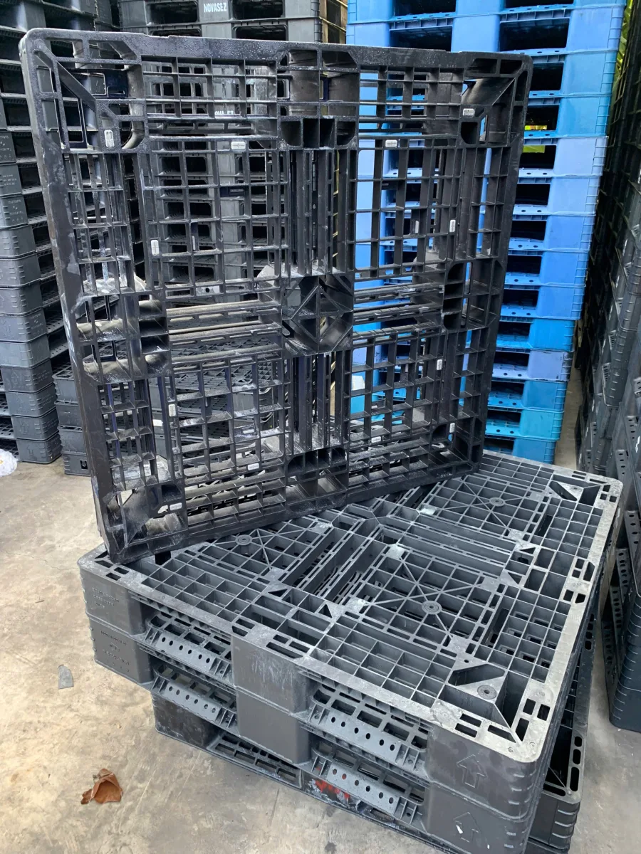 Kho pallet nhựa cũ tại Mai Trâm Plastic, pallet đen và xanh xếp chồng theo từng lô