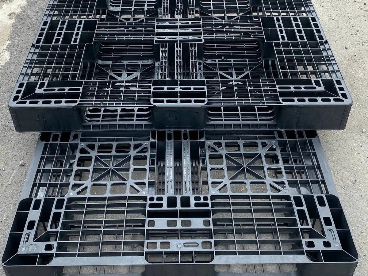 Hai tấm pallet nhựa cũ xếp chồng, thấy rõ mặt trên và khung xương mặt dưới