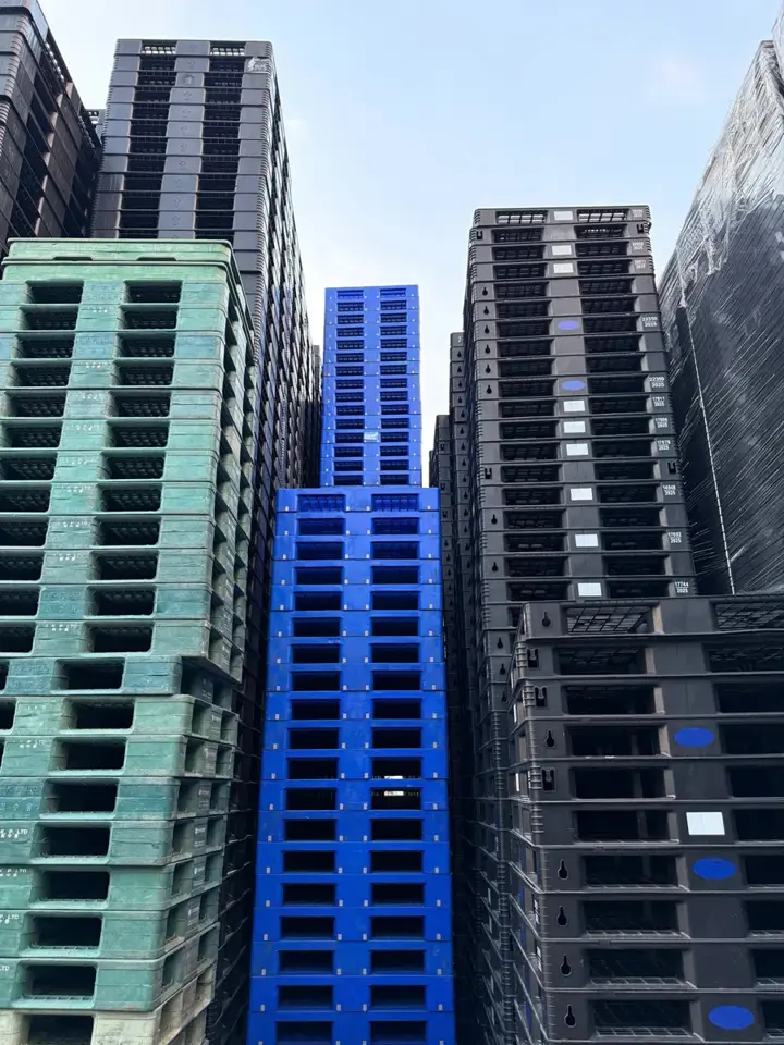 Pallet nhựa đen, xanh dương và xanh lá xếp chồng tại kho Mai Trâm